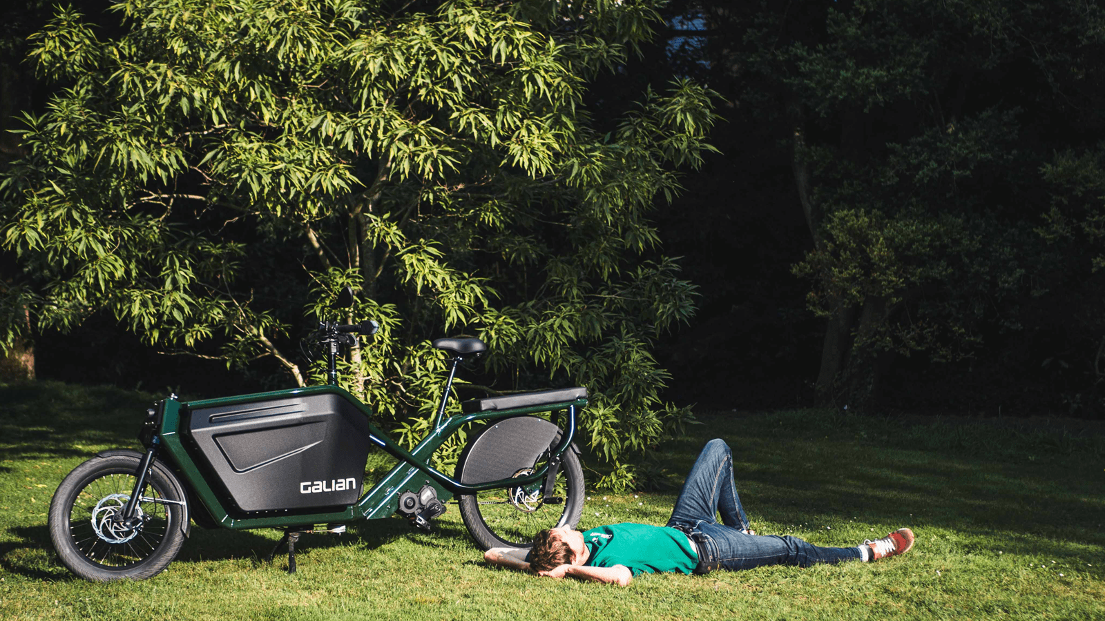 Photo d'un homme allongé paisiblement près de son cargotail dans un parc verdoyant