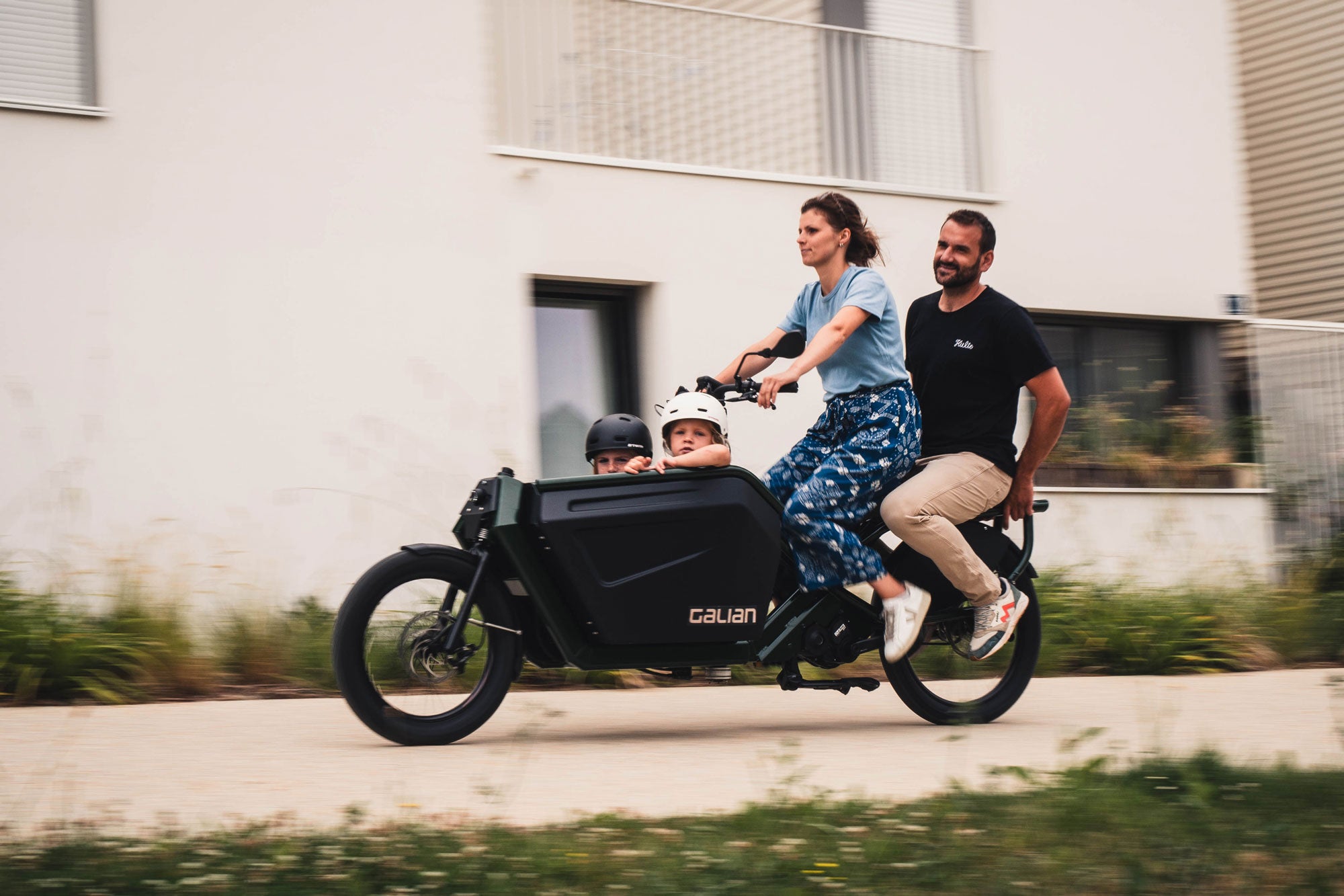 Photo avec une famille de 4 personnes à bord du vélo cargo éléctrique en déplacement 