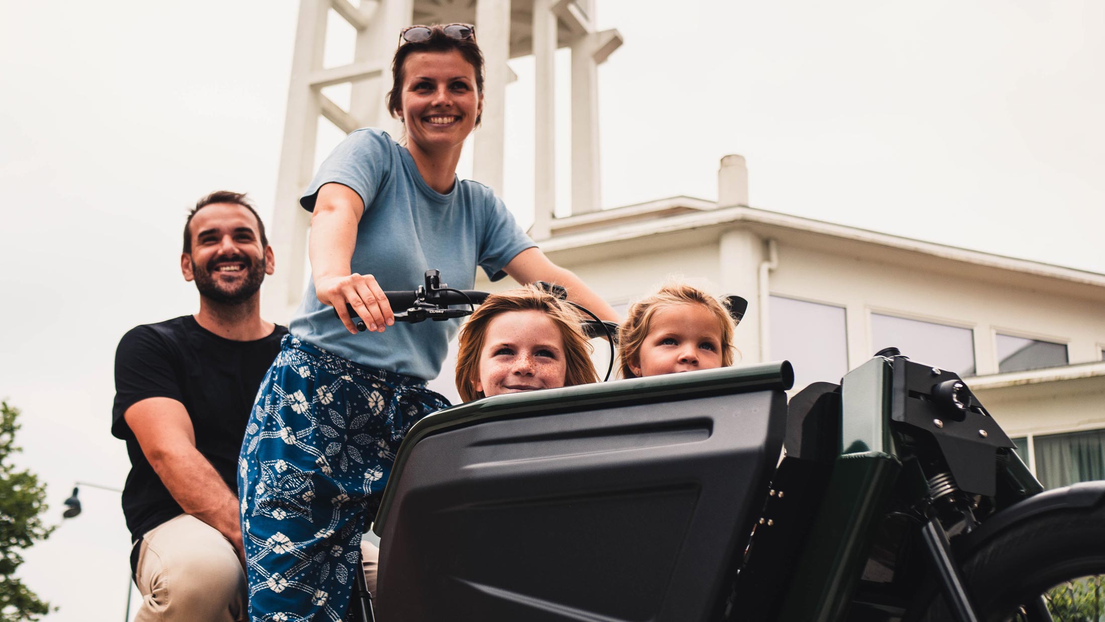 Photo d'une famille à bord du vélo électrique cargo, avec deux enfant à l'avant