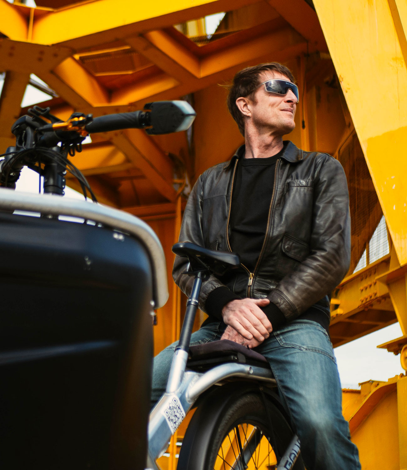 Photo d'un homme assis fièrement à l’arrière d'un vélo cargo électrique