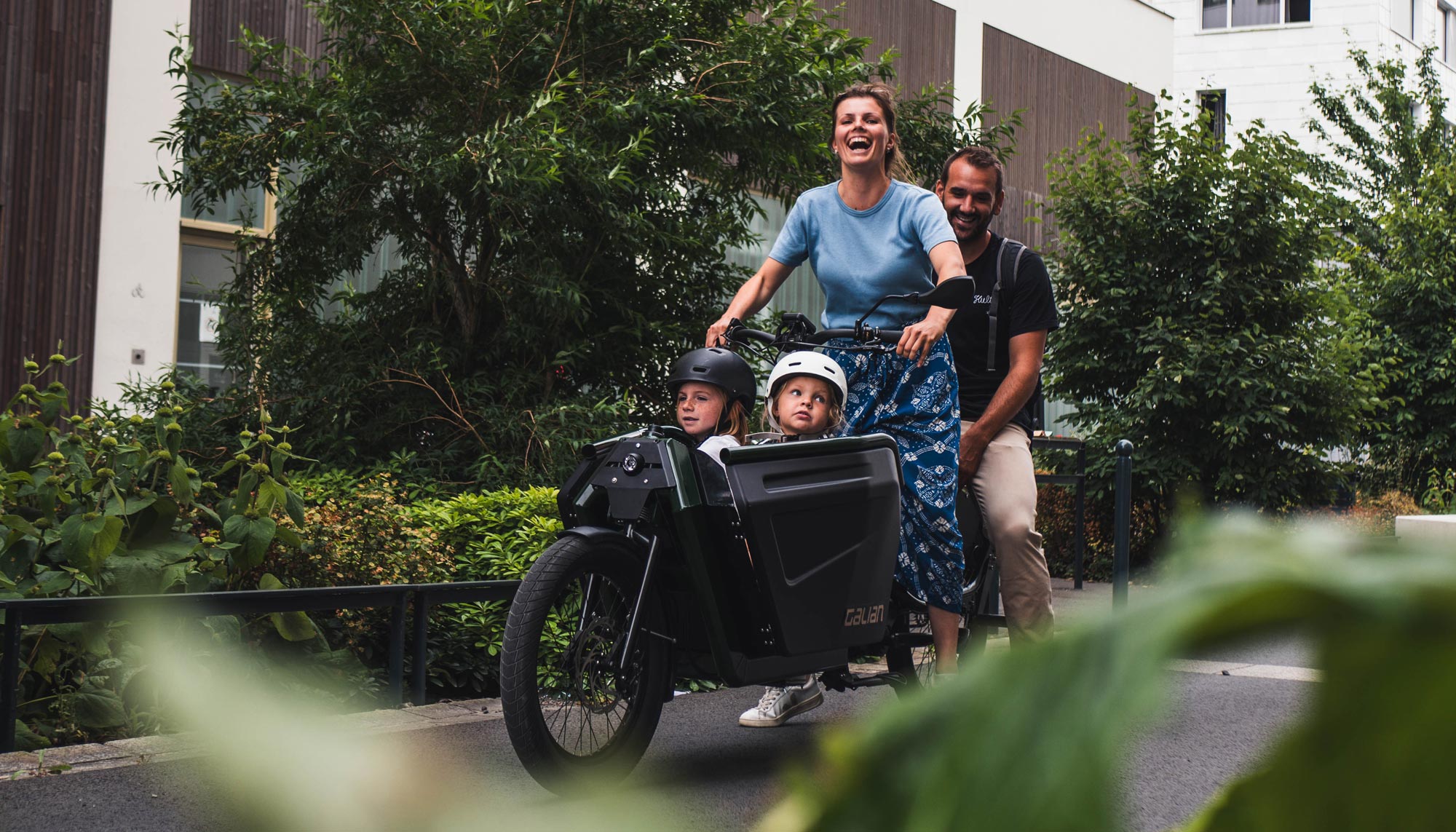 Photo d'une famille à bord du vélo électrique cargo, avec deux enfant à l'avant