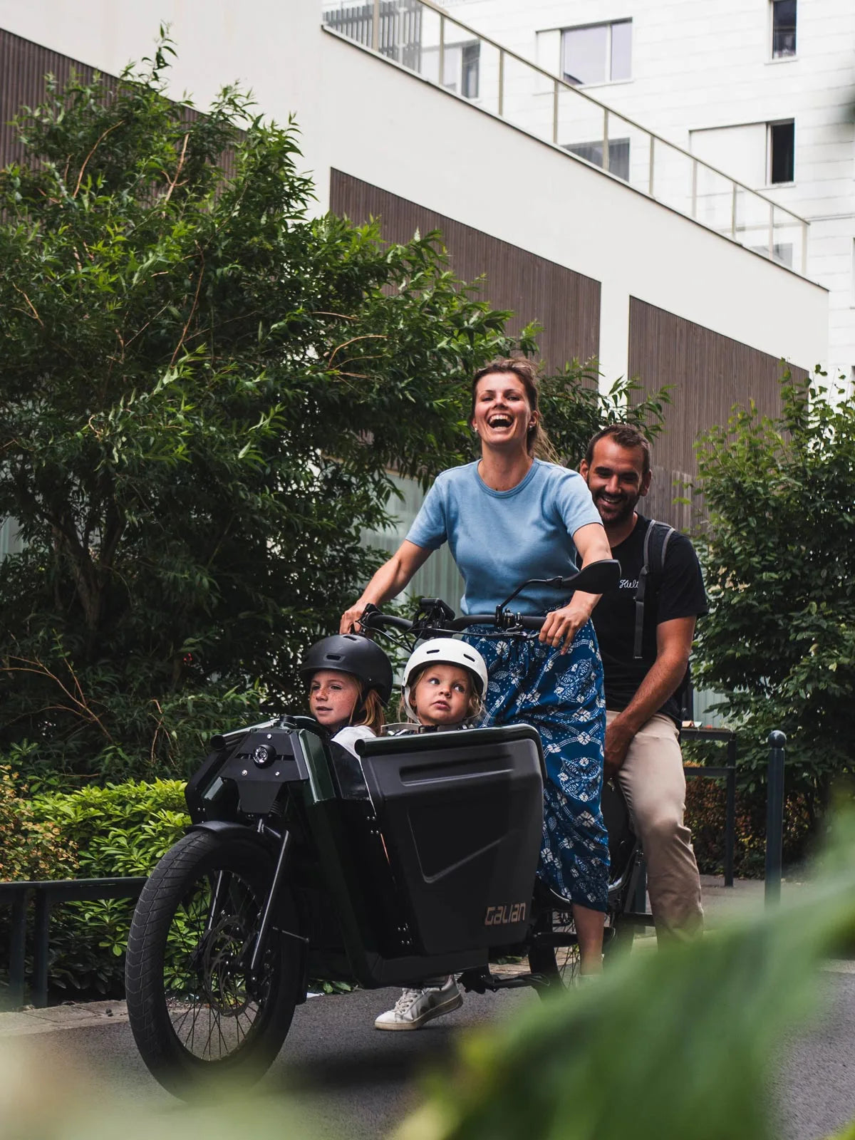 Photo portrait d'une famille à bord du vélo électrique cargo, avec 2 enfants et 2 adultes